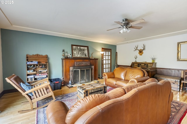 living room featuring ceiling fan, a brick fireplace, and light hardwood / wood-style flooring