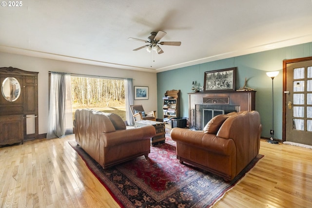 living room with a fireplace, ceiling fan, and light wood-type flooring