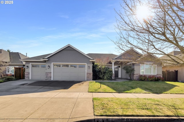 view of front facade with a garage, fence, concrete driveway, stone siding, and a front lawn