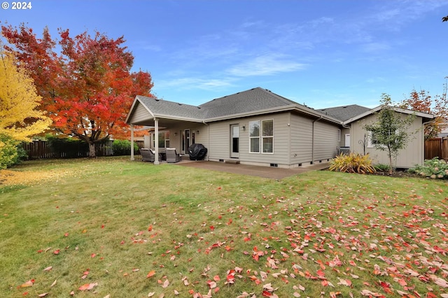 back of property with a lawn, a patio area, and fence