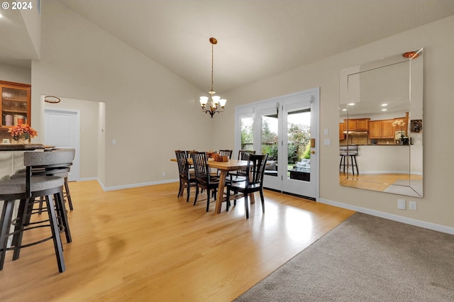 dining area with baseboards, high vaulted ceiling, an inviting chandelier, and light wood-style floors