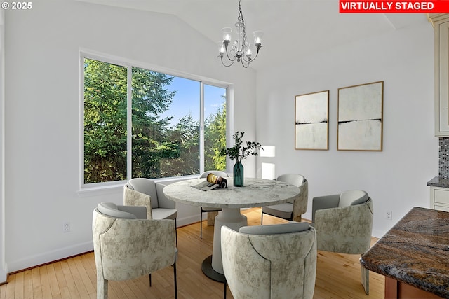 dining area featuring light hardwood / wood-style floors, a chandelier, and lofted ceiling