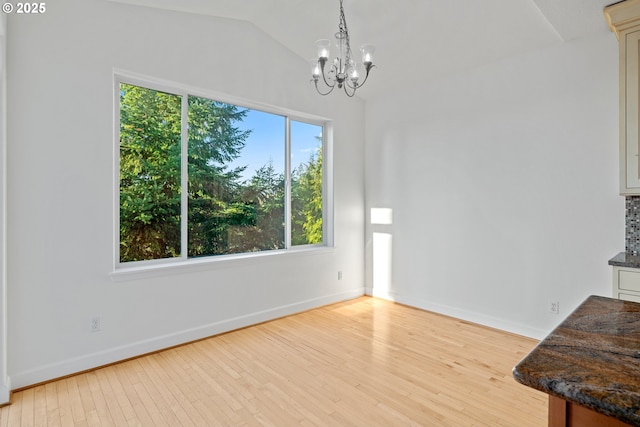 unfurnished dining area with light wood-type flooring, lofted ceiling, and a notable chandelier