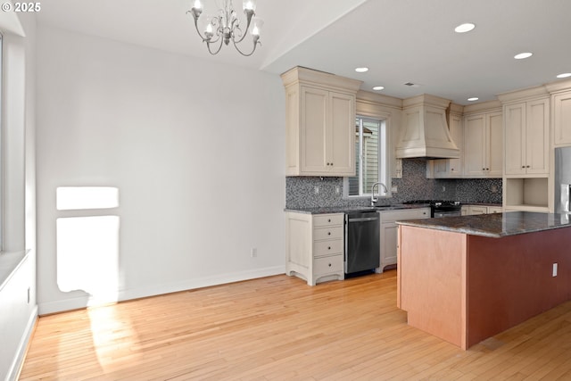 kitchen featuring premium range hood, dishwasher, range with gas stovetop, decorative light fixtures, and tasteful backsplash