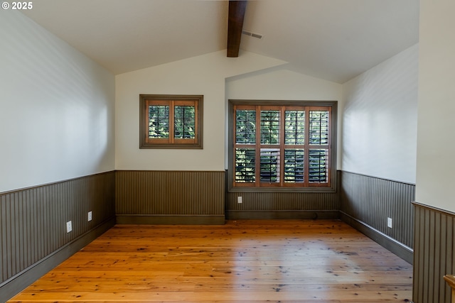 spare room with hardwood / wood-style flooring and lofted ceiling with beams