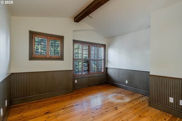 unfurnished room with vaulted ceiling with beams and light wood-type flooring