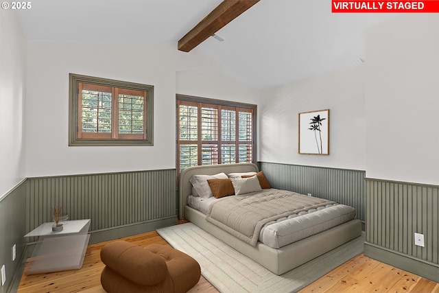 bedroom featuring light hardwood / wood-style floors and vaulted ceiling with beams