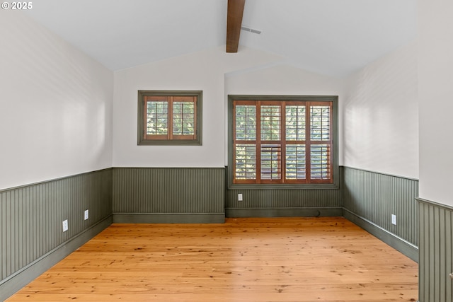 unfurnished room with lofted ceiling with beams and light hardwood / wood-style flooring