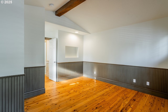 unfurnished room featuring vaulted ceiling with beams and light wood-type flooring