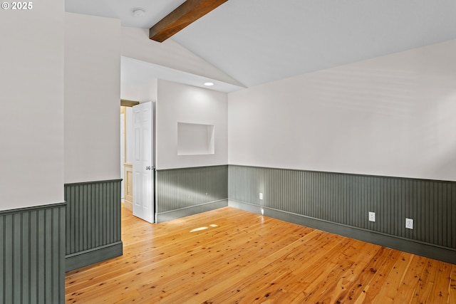 unfurnished room with light wood-type flooring and vaulted ceiling with beams