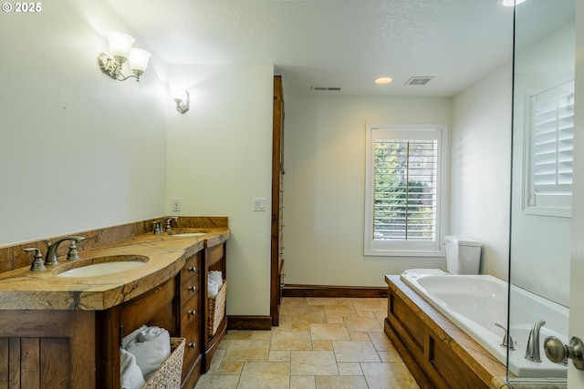 bathroom featuring vanity, a tub to relax in, and a textured ceiling