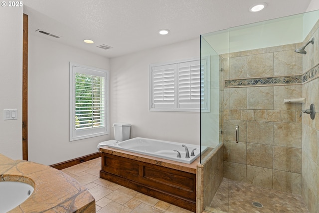 bathroom featuring a textured ceiling, vanity, and plus walk in shower