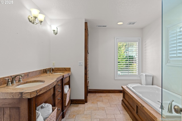 bathroom featuring a textured ceiling, a tub, and vanity