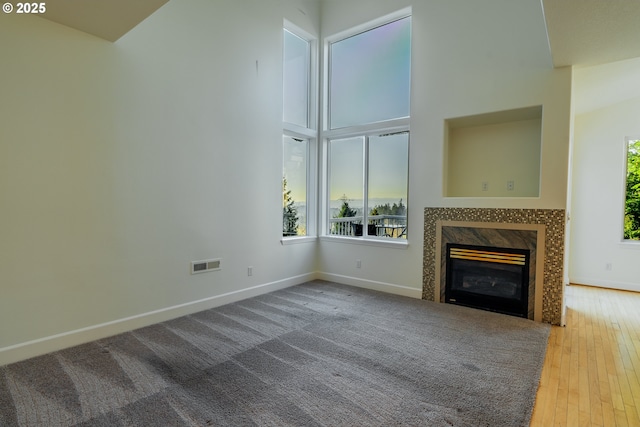 unfurnished living room with wood-type flooring, a fireplace, and a high ceiling