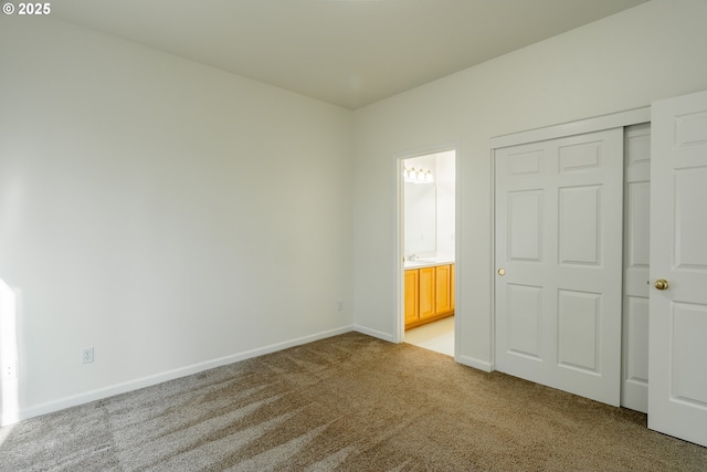 unfurnished bedroom featuring sink, a closet, ensuite bathroom, and carpet flooring