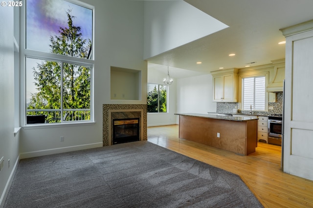 kitchen with an inviting chandelier, a center island, light hardwood / wood-style flooring, pendant lighting, and decorative backsplash