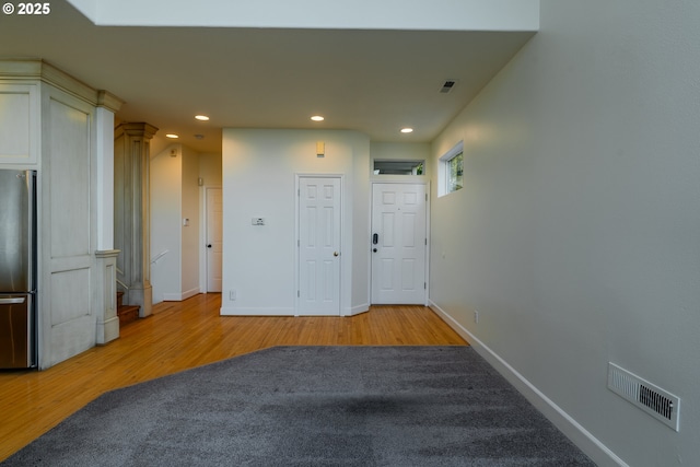 hall with ornate columns and light hardwood / wood-style flooring