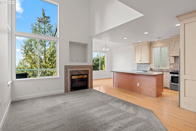 kitchen with sink, cream cabinetry, stainless steel range, a fireplace, and decorative backsplash