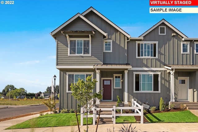 view of front of property with a front yard, fence, board and batten siding, and metal roof