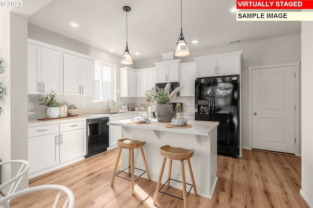 kitchen with a sink, visible vents, black appliances, and white cabinets