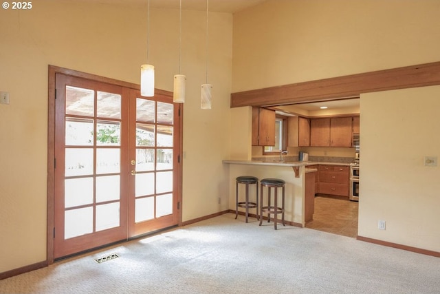 2116 Sally Way, Eugene, OR 97401 - kitchen featuring light carpet, a breakfast bar area, french doors, a towering ceiling, and brown cabinets