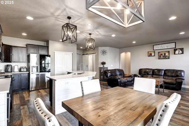 dining space with a barn door, sink, dark wood-type flooring, and a textured ceiling