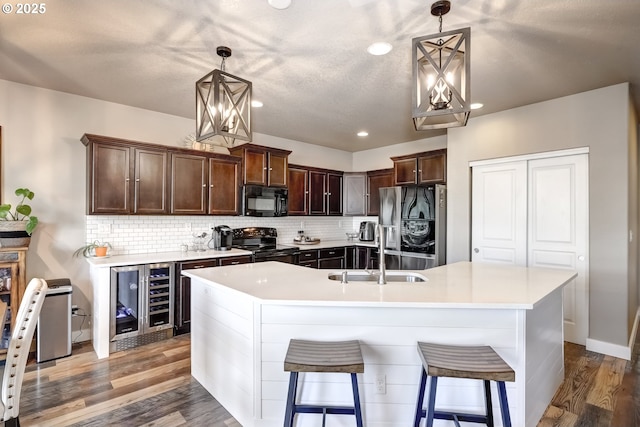 kitchen featuring sink, hanging light fixtures, black appliances, decorative backsplash, and beverage cooler