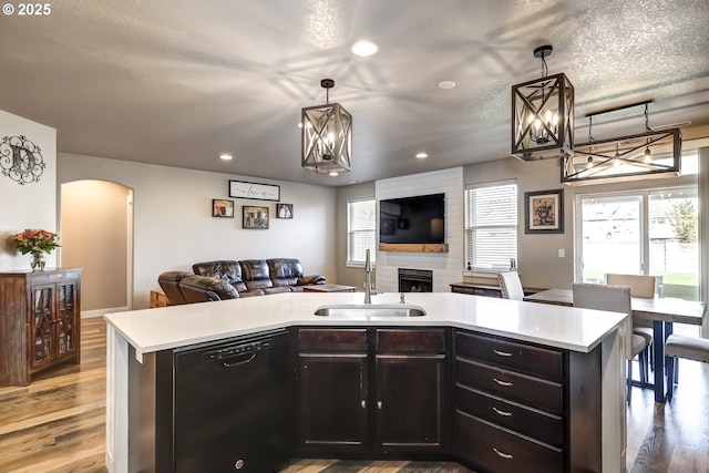 kitchen featuring sink, hanging light fixtures, black dishwasher, and a center island with sink