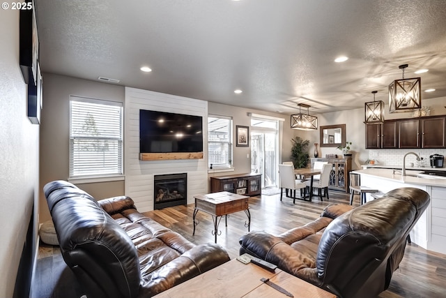 living room featuring wood-type flooring, a textured ceiling, and a fireplace