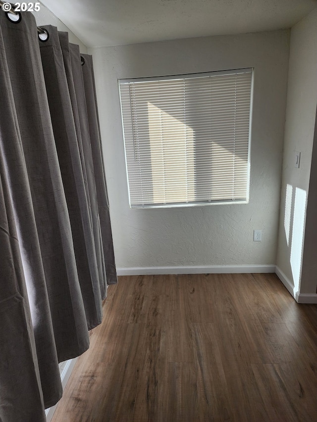 unfurnished room featuring dark wood-style floors and baseboards