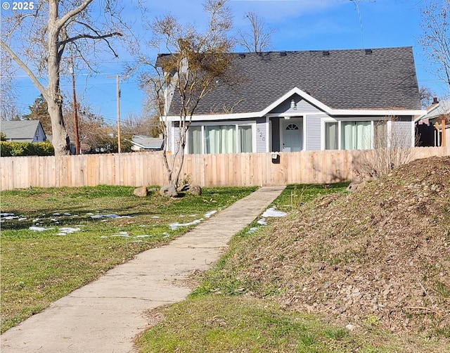 bungalow featuring fence, a front lawn, and roof with shingles