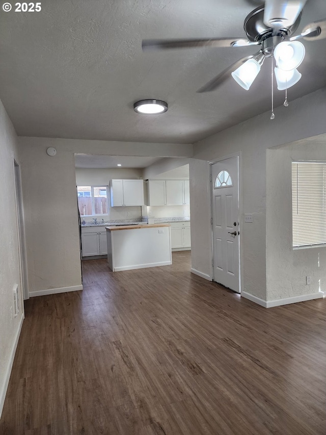 kitchen with light countertops, dark wood-type flooring, open floor plan, white cabinetry, and a textured ceiling