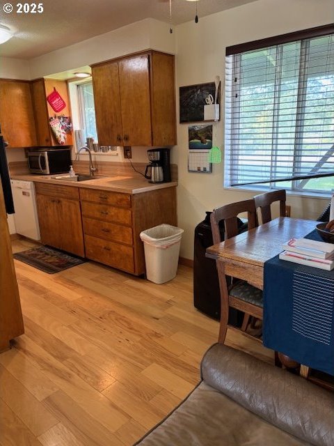 34851 Seavey Loop Rd, Eugene, OR 97405 - kitchen featuring brown cabinetry, stainless steel microwave, light wood-style flooring, and light countertops