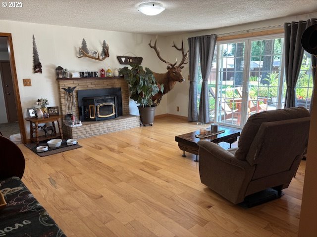 34851 Seavey Loop Rd, Eugene, OR 97405 - living room featuring wood finished floors, a textured ceiling, and a wood stove