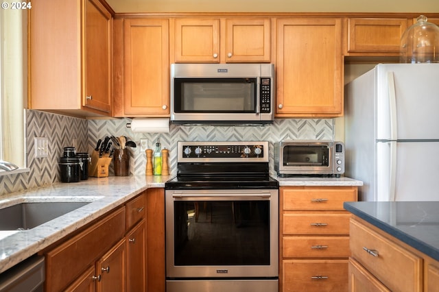 kitchen featuring appliances with stainless steel finishes, tasteful backsplash, light stone counters, and sink