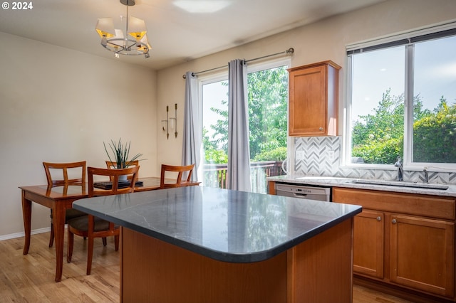 kitchen with sink, hanging light fixtures, tasteful backsplash, light hardwood / wood-style floors, and a kitchen island