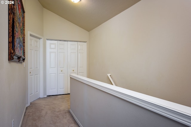 hall featuring light colored carpet and lofted ceiling