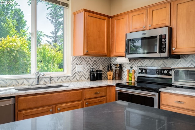 kitchen featuring sink, light stone countertops, stainless steel appliances, and a wealth of natural light