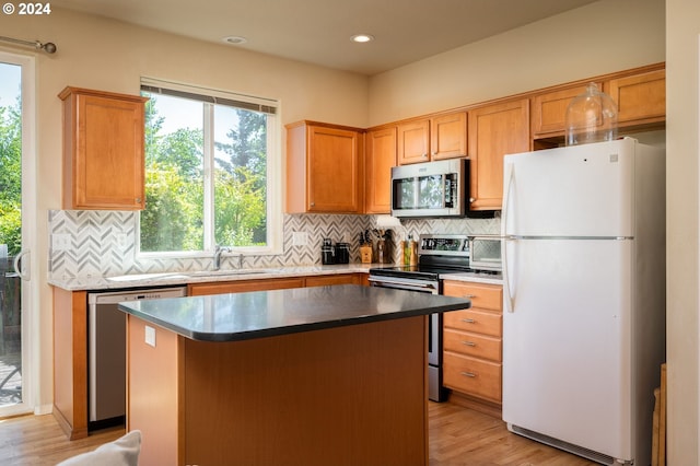 kitchen with appliances with stainless steel finishes, light hardwood / wood-style flooring, a kitchen island, and sink