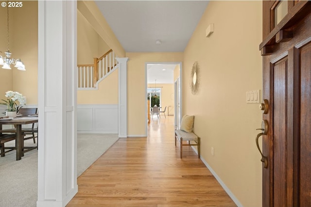 3816 NW Tustin Ranch Dr, Portland, OR 97229 - hallway with light wood finished floors, a wainscoted wall, a chandelier, and stairs