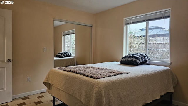 bedroom featuring multiple windows, light floors, baseboards, and a closet