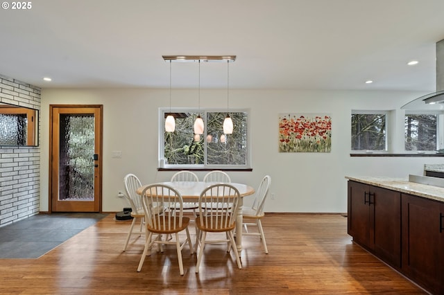 dining space with light hardwood / wood-style flooring and brick wall