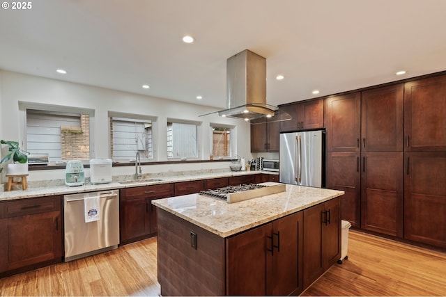 kitchen with sink, island range hood, a kitchen island, stainless steel appliances, and light stone countertops