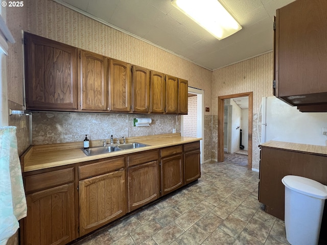 2909 College St, Baker City, OR 97814 - kitchen featuring wallpapered walls, light countertops, stone finish flooring, freestanding refrigerator, and brown cabinets