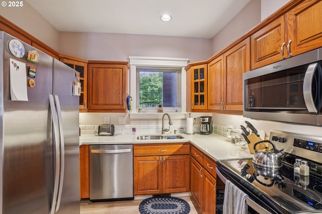 240 NE 5th St, Gresham, OR 97030 - kitchen featuring appliances with stainless steel finishes, a sink, light countertops, brown cabinetry, and glass insert cabinets