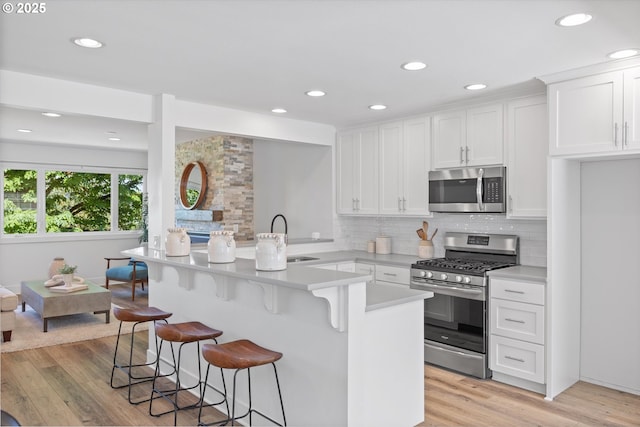 13756 John Jeffrey Ct, Oregon City, OR 97045 - kitchen featuring stainless steel appliances, a sink, white cabinetry, decorative backsplash, and a kitchen breakfast bar