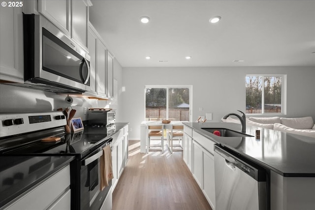 kitchen with sink, light hardwood / wood-style floors, white cabinetry, and stainless steel appliances