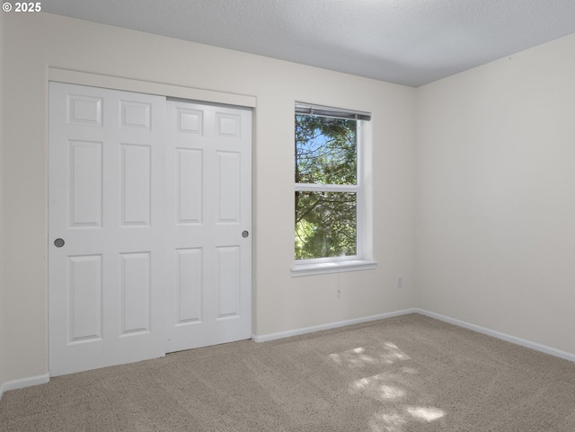 unfurnished bedroom with a closet, baseboards, and carpet flooring