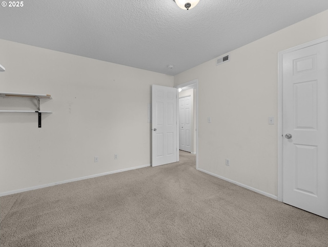 unfurnished bedroom featuring carpet flooring, a textured ceiling, visible vents, and baseboards
