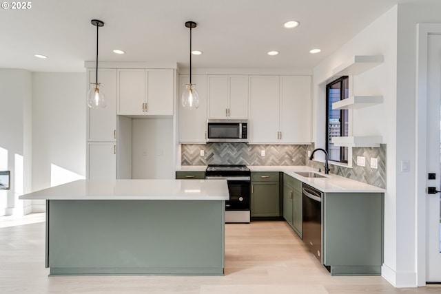 kitchen with sink, white cabinetry, decorative light fixtures, appliances with stainless steel finishes, and a kitchen island